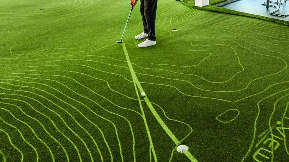 A golfer putting on a PuttView green with projected contour lines